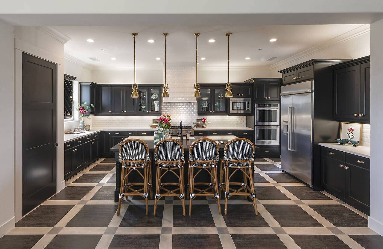 Black cabinet kitchen with checkerboard floor, brass pendants and marble countertops